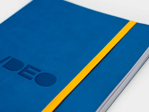 Nahaufnahme des blauen Softcovers eines A5-Kalenders mit Logo und gelbem Gummiband