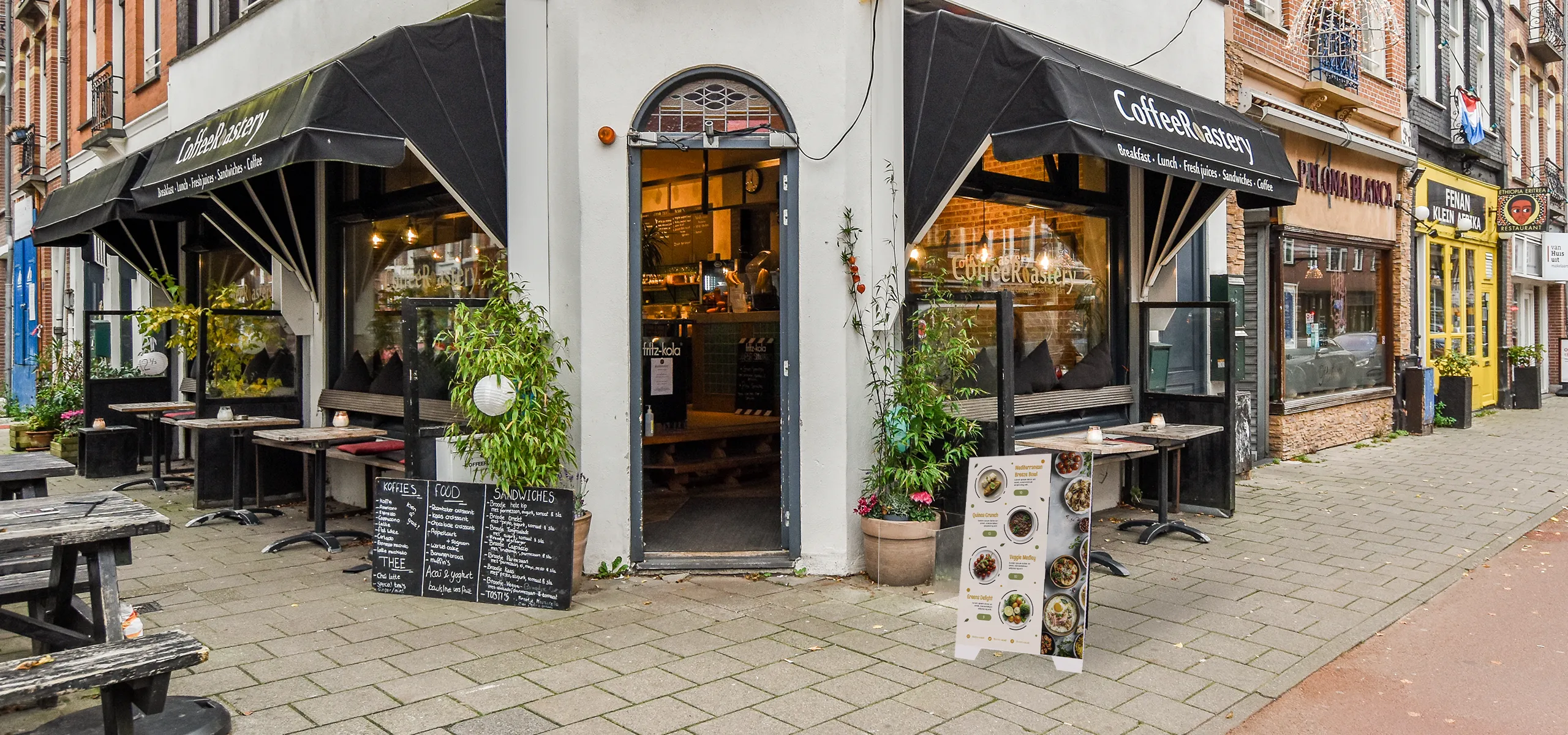 Doppelseitiger PVC-Werbeaufsteller mit Speisekarte vor einem Café